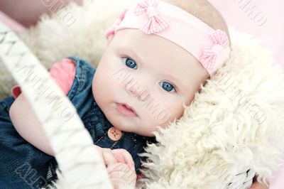 cute newborn baby girl in a basket on white fur 