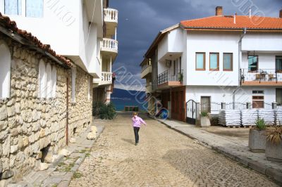 Girl runs on the street of the seaside town to the sea Girl runs on the street of the seaside town to the sea