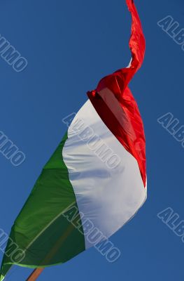 A large Italian flag in the blue sky free