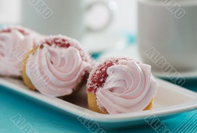 Three cakes with pink cream on a blue background