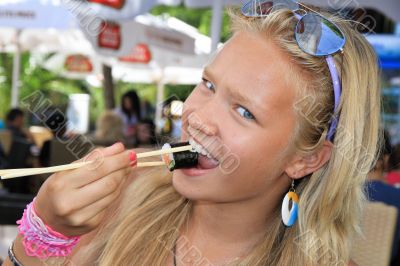 Pretty young blonde eats sushi.