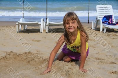 Little six-year-girl playing in the sand on the beach.