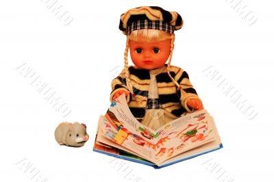 The doll is holding an open book.