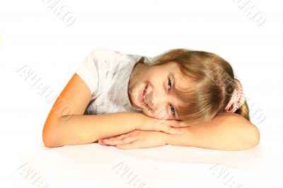 Beautiful little girl sitting at the table. She smiles and looks into the camera.