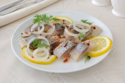 Slices of salted herring with onion, lemon and spices