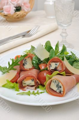 Rolls of jamon with blue cheese in the mix of lettuce with Parme