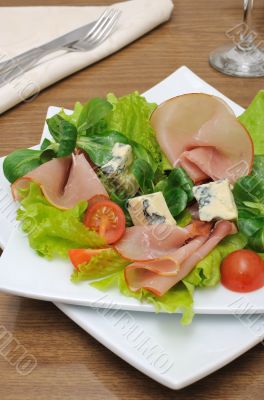 Appetizer with slices of jamon and blue cheese with cherry