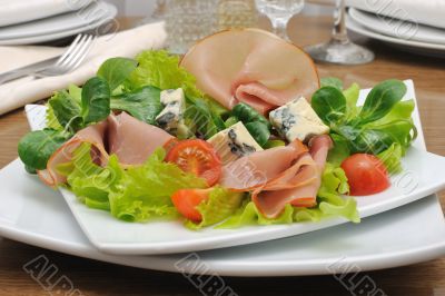 Appetizer with slices of jamon and blue cheese with cherry