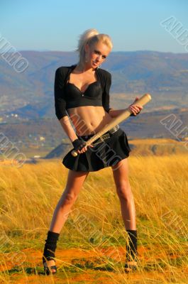 Sexy blonde girl with the bat against the sky