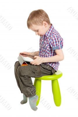 boy with a Tablet PC sitting on a green children`s chair