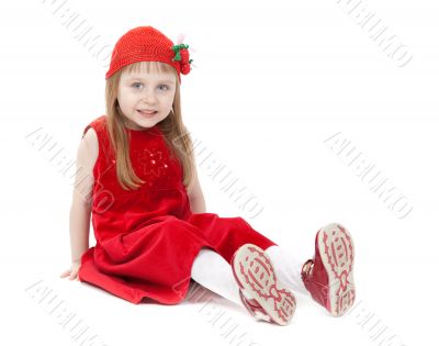 A girl aged four years in a red dress sitting on the floor