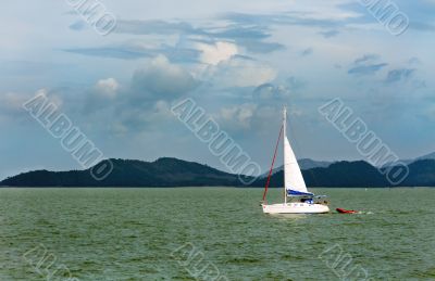 white sailboat in the background of the tropical islands