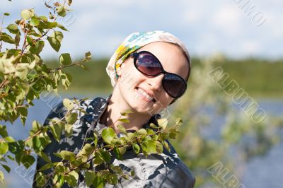 Portrait of a blond girl behind the green bush