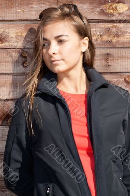 portrait of a young girl standing against a wooden wall portrait of a young girl standing against a wooden wall