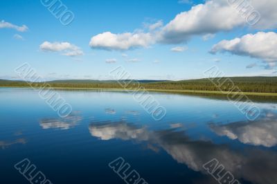 Calm beautiful rural landscape with a lake and sky reflected