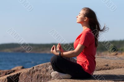 Young girl in lotus pose on the rocks