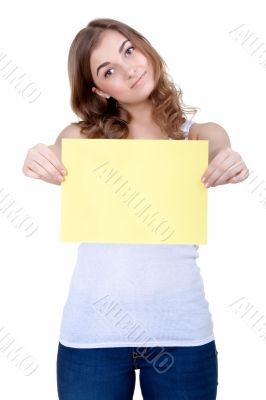 Beautiful young girl shows a blank sheet of yellow