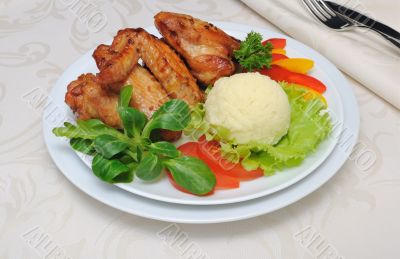 Baked chicken wings with garlic and potatoes and vegetables