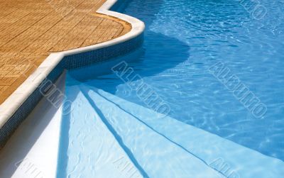 Steps to the swimming pool. Rippled water under sunlight