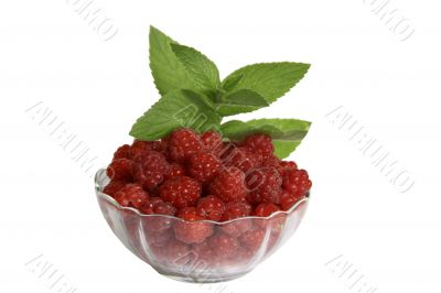 Berries of raspberry in a glass vase with the leaves of mint