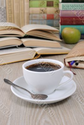 A cup of coffee on a table among books