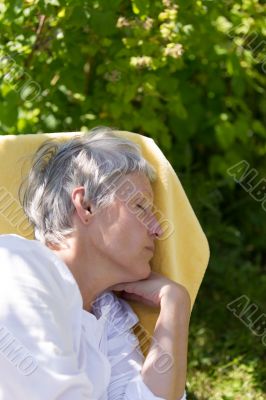 Aged woman sleeping on lounger