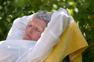 Senior woman sleeping on lounger