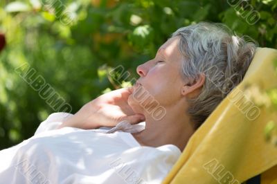 Aged woman sleeping on lounger