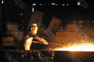 worker using torch cutter to cut through metal 