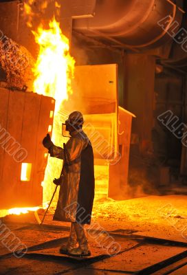 A steel worker takes a sample from oven