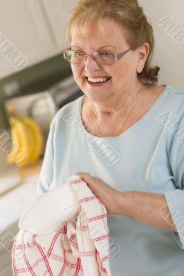 Senior Adult Woman Drying Bowl At Sink in Kitchen Senior Adult Woman Drying Bowl At Sink in Kitchen