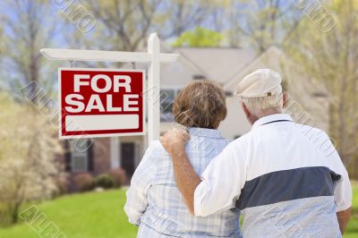 Happy Senior Couple Front of For Sale Sign and House