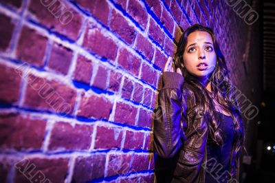 Frightened Pretty Young Woman Against Brick Wall at Night Frightened Pretty Young Woman Against Brick Wall at Night