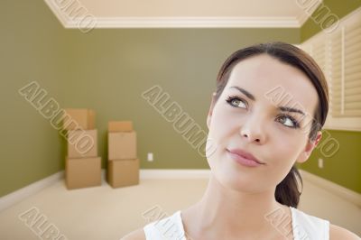 Contemplative Young Woman Daydreaming in Empty Room with Boxes Contemplative Young Woman Daydreaming in Empty Room with Boxes