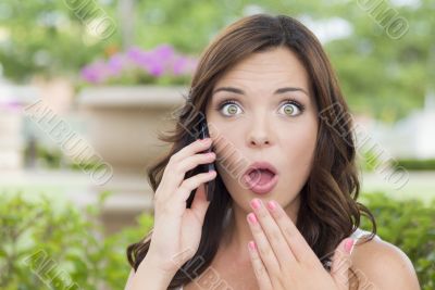 Shocked Young Adult Female Talking on Cell Phone Outdoors