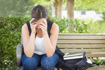 Upset Young Woman Sitting Alone on Bench Next to Books