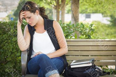 Upset Young Woman Sitting Alone on Bench Next to Books