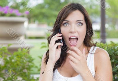 Shocked Young Adult Female Talking on Cell Phone Outdoors