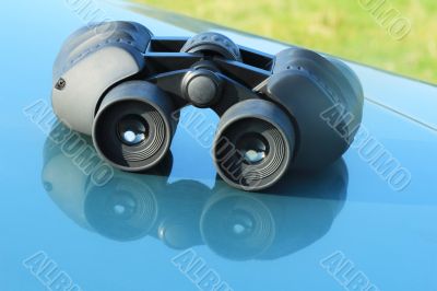 Binoculars lying on the car hood.