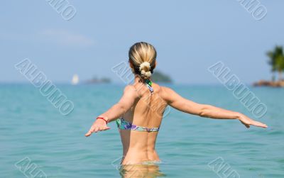 Beautiful young slim girl in the water in the sea, looking away