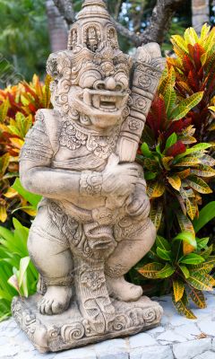 Thai stone god in the bushes of tropical plants