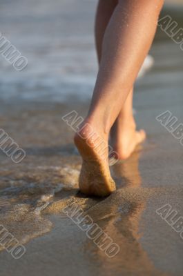 Beautiful woman legs on the beach at sunset