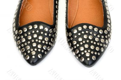Black women`s leather ballet flats with steel rivets close up 