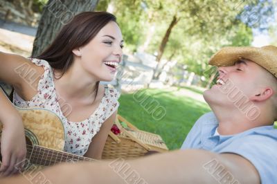 Mixed Race Couple with Guitar and Cowboy Hat in Park