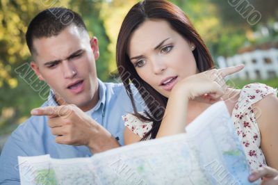 Lost and Confused Mixed Race Couple Looking Over Map Outside