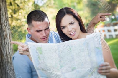 Lost and Confused Mixed Race Couple Looking Over Map Outside