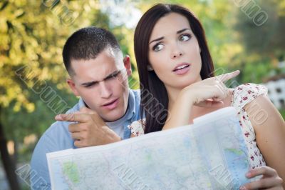 Lost and Confused Mixed Race Couple Looking Over Map Outside