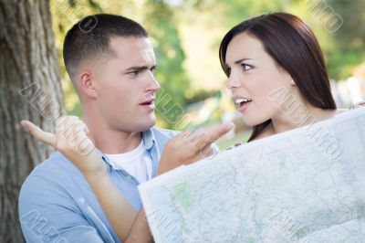 Lost and Confused Mixed Race Couple Looking Over Map Outside