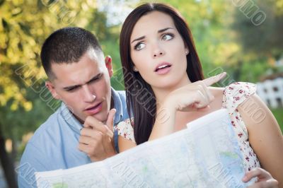 Lost and Confused Mixed Race Couple Looking Over Map Outside