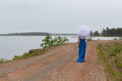Slim girl in a dress with an umbrella in a forest